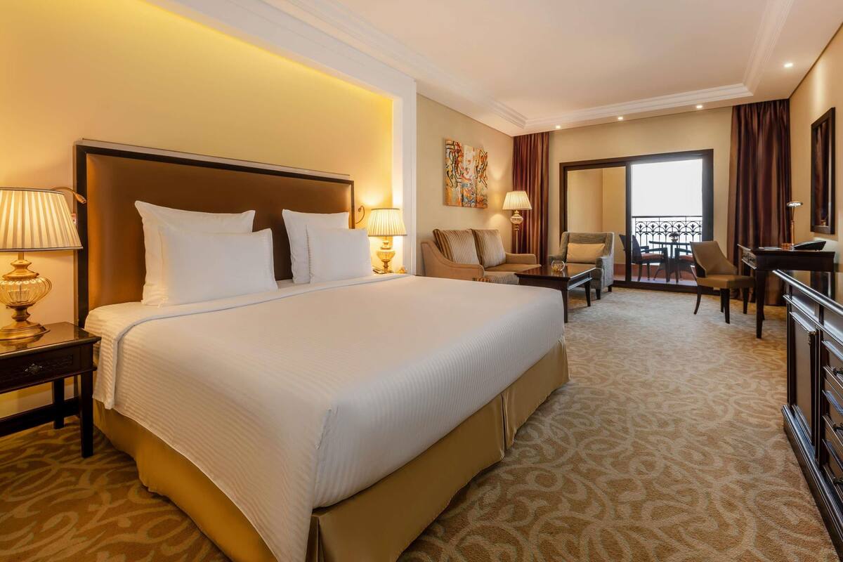 Une chambre d’hôtel avec un grand lit, un bureau, une chaise et un balcon avec vue.
