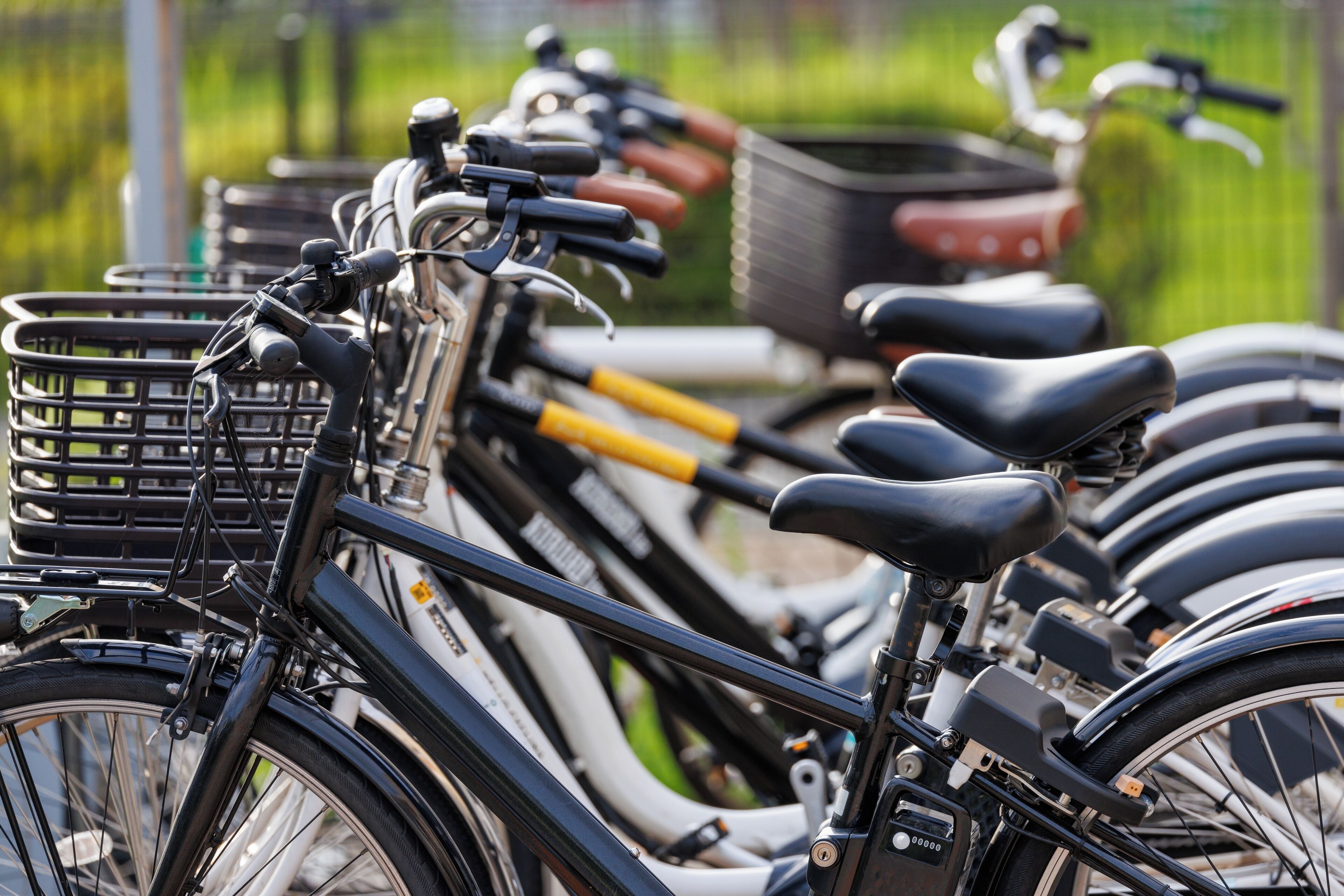 Une rangée de vélos, garés très près les uns des autres, chacun muni d’un panier et d’une sonnette.