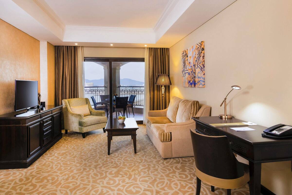 Une chambre d’hôtel équipée d’une télévision, d’un canapé, d’un bureau et d’un balcon avec vue.