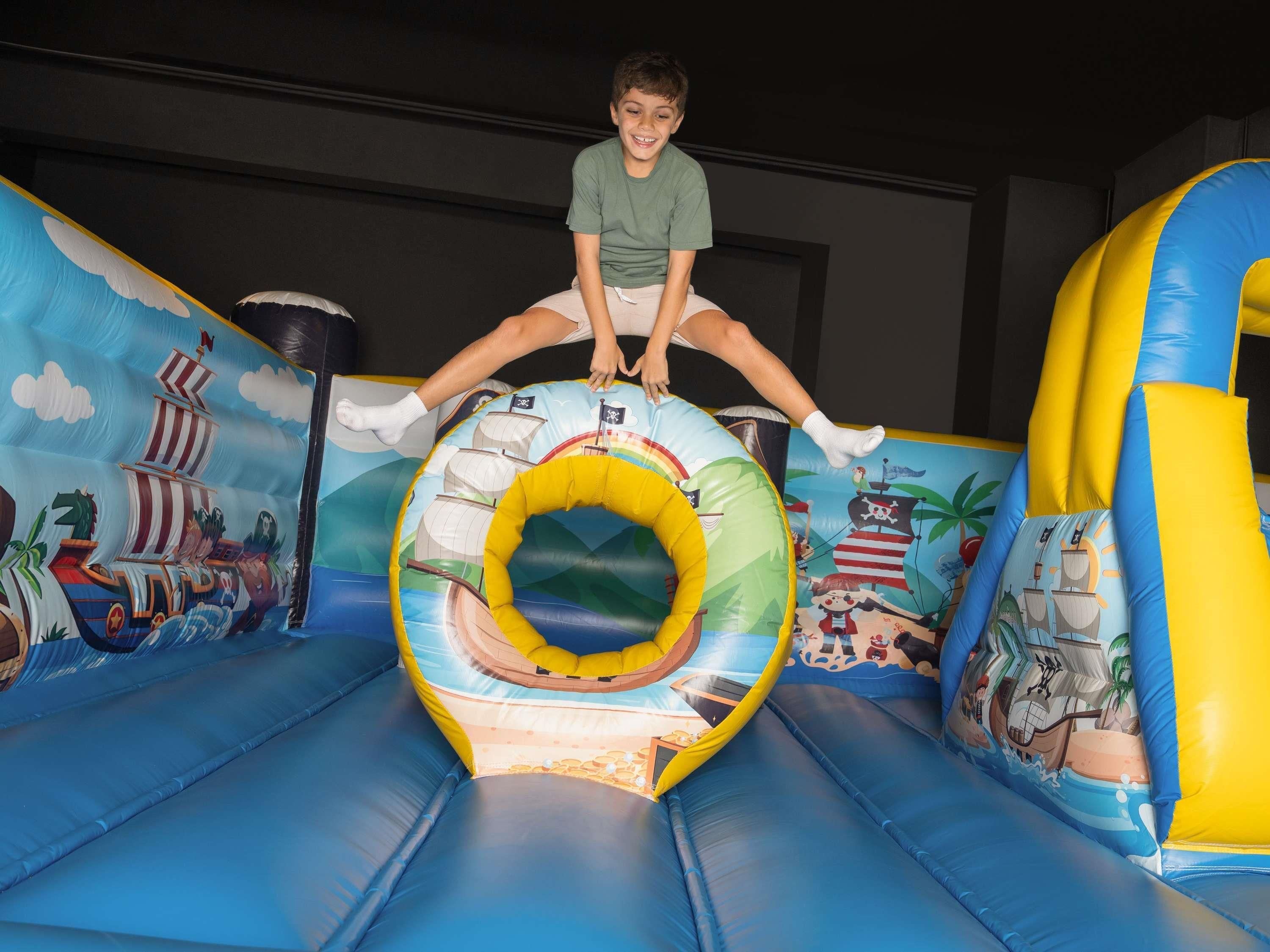 A child sliding down a colorful inflatable slide with maritime and beach-themed designs.