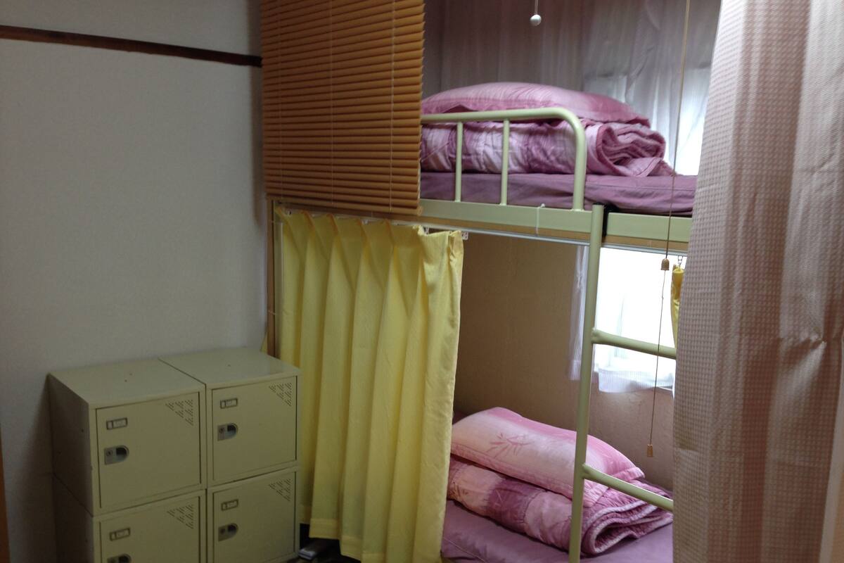 A bunk bed room with a window, a curtain, and storage boxes.