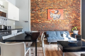 Une cuisine moderne avec des meubles blancs, un plan de travail noir et un mur en briques.