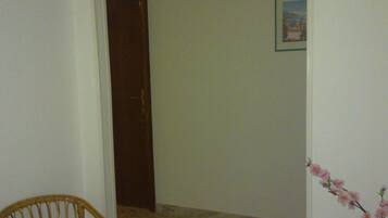 A hallway with a wooden chair, a door, and a framed picture on the wall.