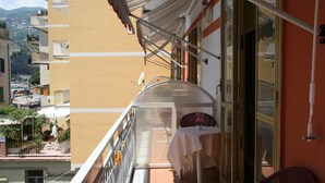 A balcony with a table and chairs, a view of the city, and a building with balconies. - B&B Vittoria (Maiori)