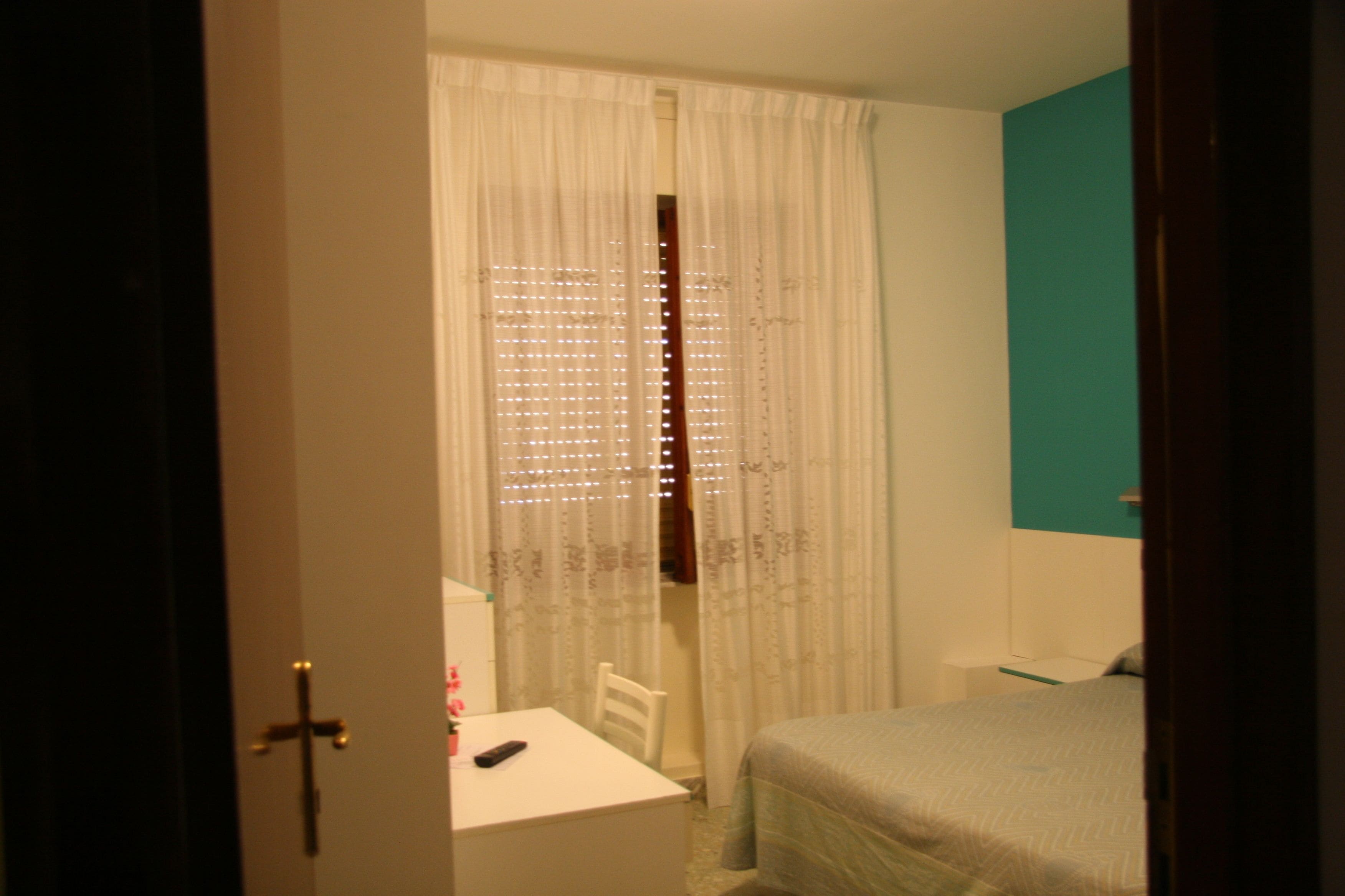 A bedroom with a bed, a desk, and a chair.