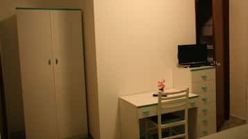 Un dormitorio con cama, escritorio con silla, armario y televisor.