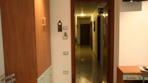 A hallway with a wooden door, a mirror, and a desk with a chair. - B&B Vittoria (Maiori)