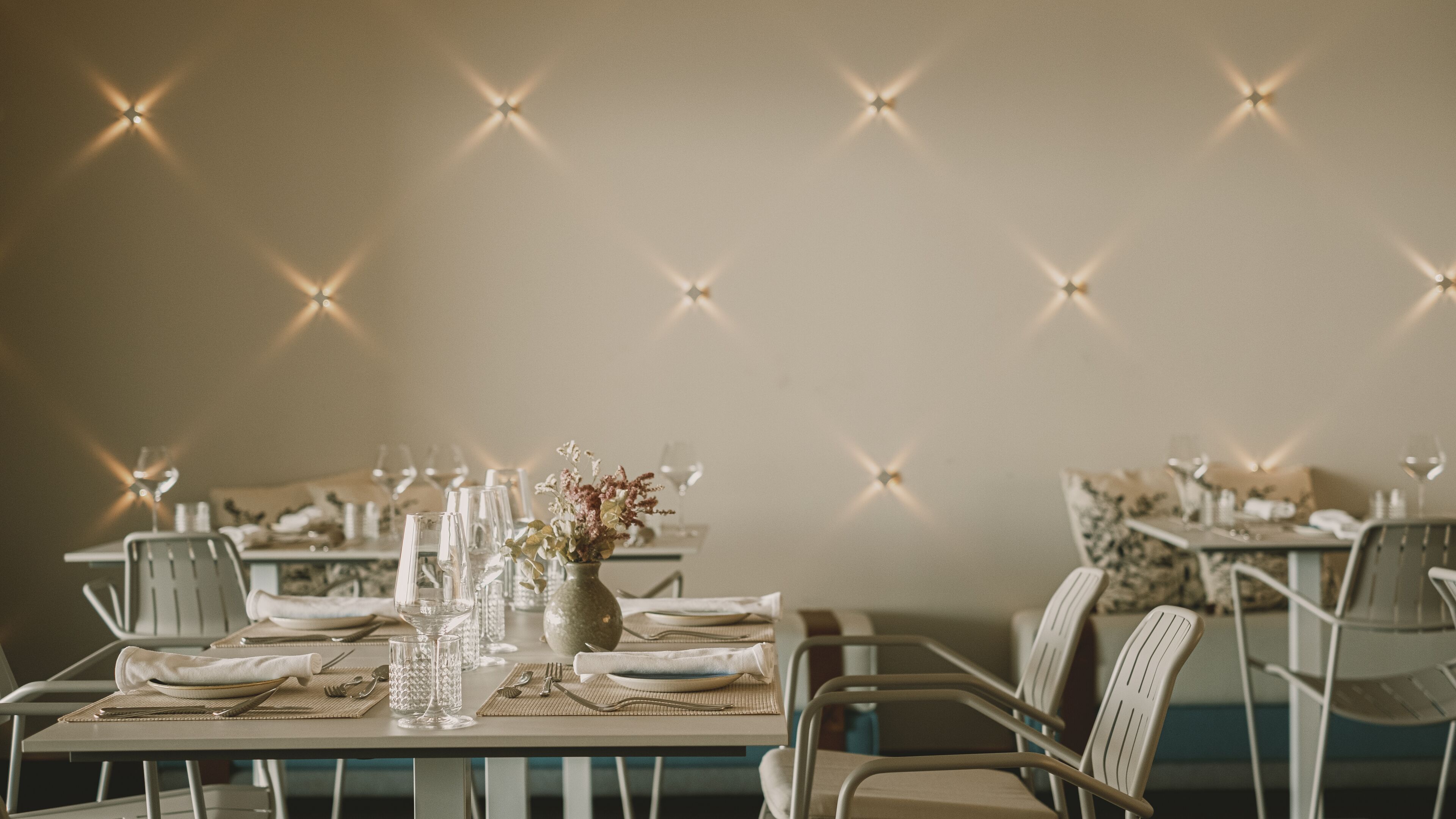 Un espace repas avec des tables mises pour le repas, comprenant de la vaisselle transparente, des assiettes et un centre de table.