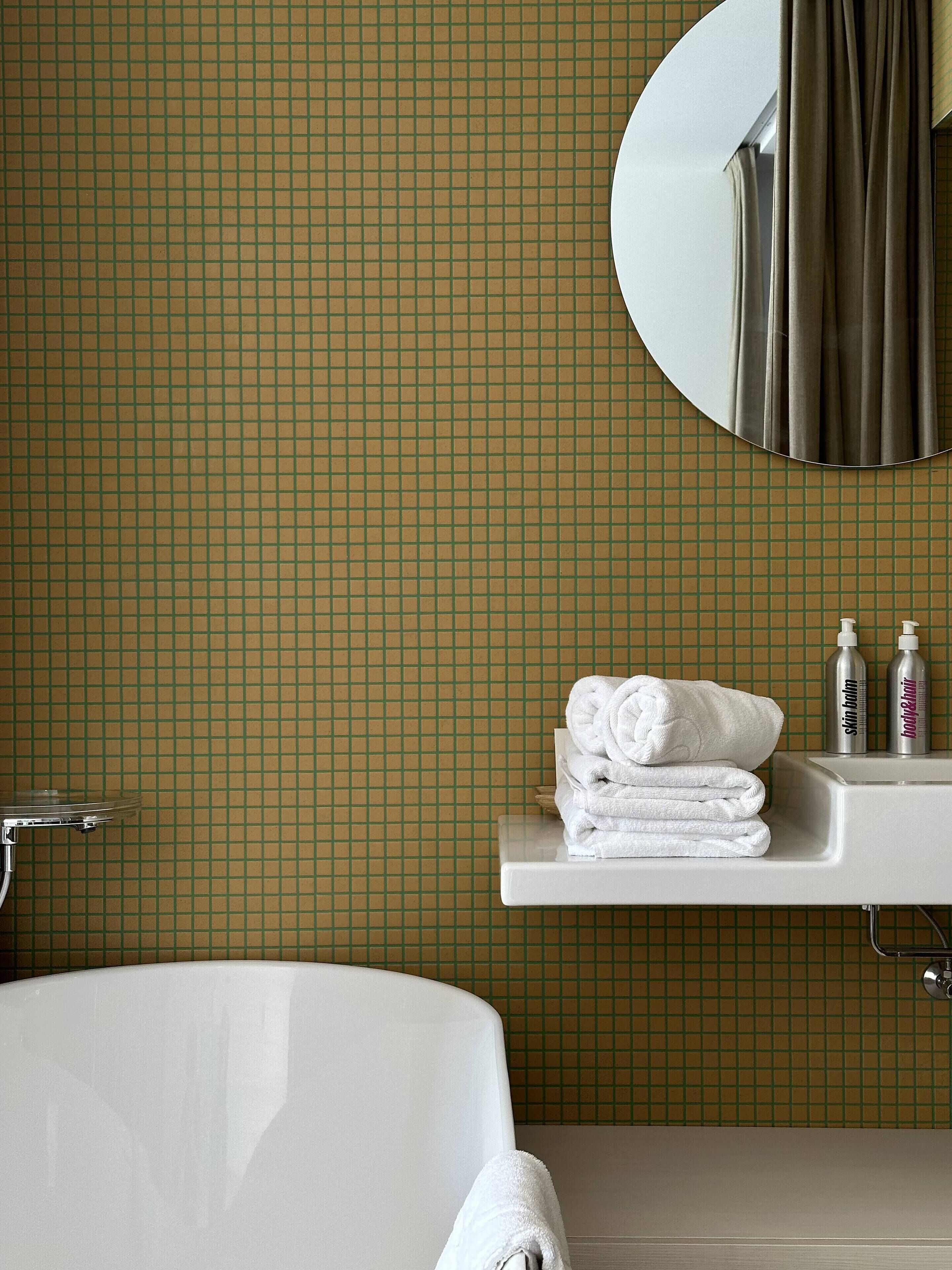 A bathroom with a bathtub, a sink with toiletries, and a mirror.