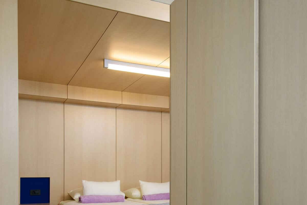 A compact bedroom with a bed, a nightstand, and a built-in desk.