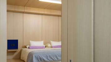 Un dormitorio compacto con cama, mesita de noche y escritorio integrado.