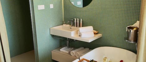 Un baño con una bañera llena de pétalos de rosa, un lavamanos, un espejo y una zona de ducha.