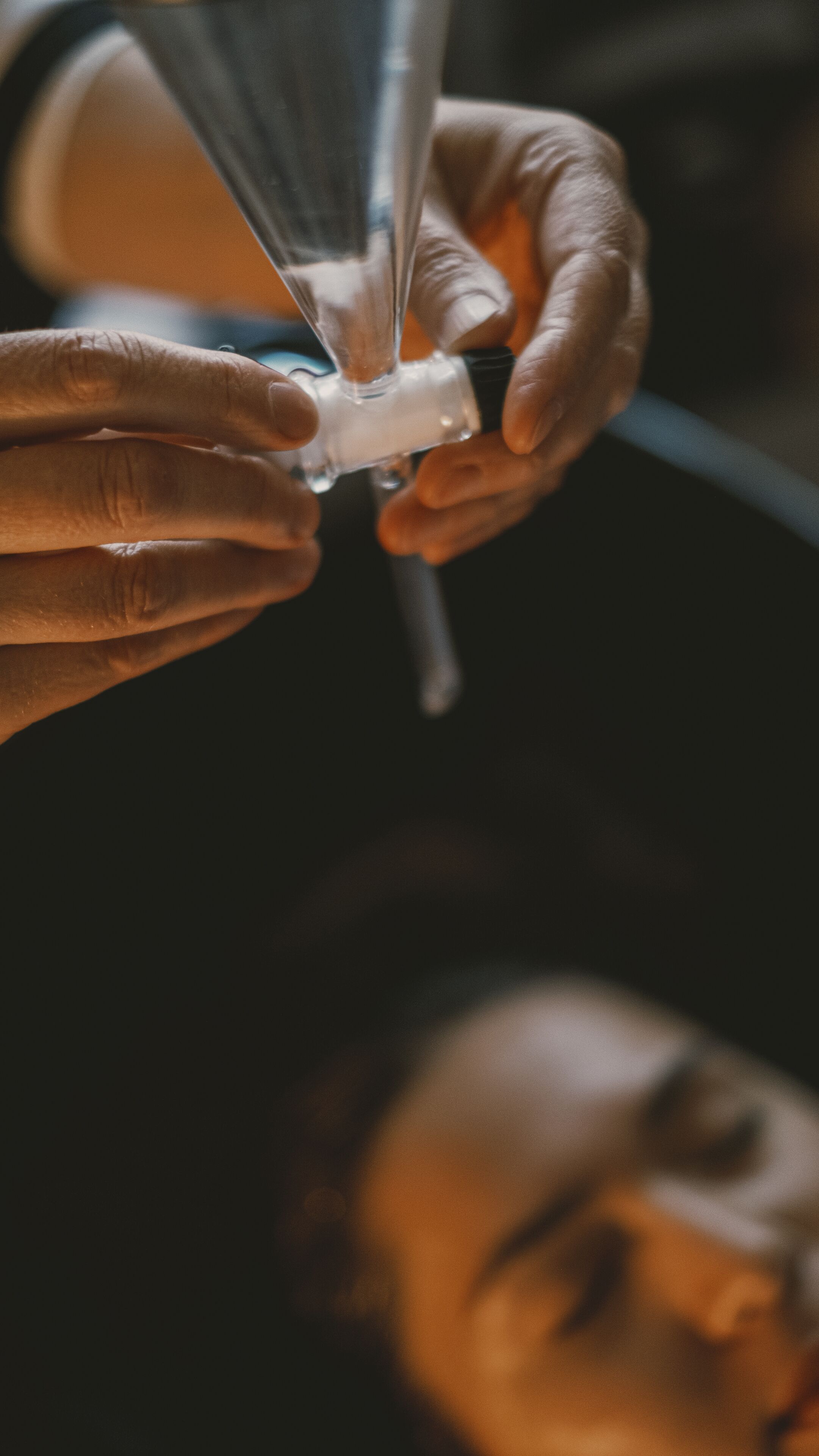 Un primo piano di mani che tengono un oggetto trasparente, forse un bicchiere o di plastica.