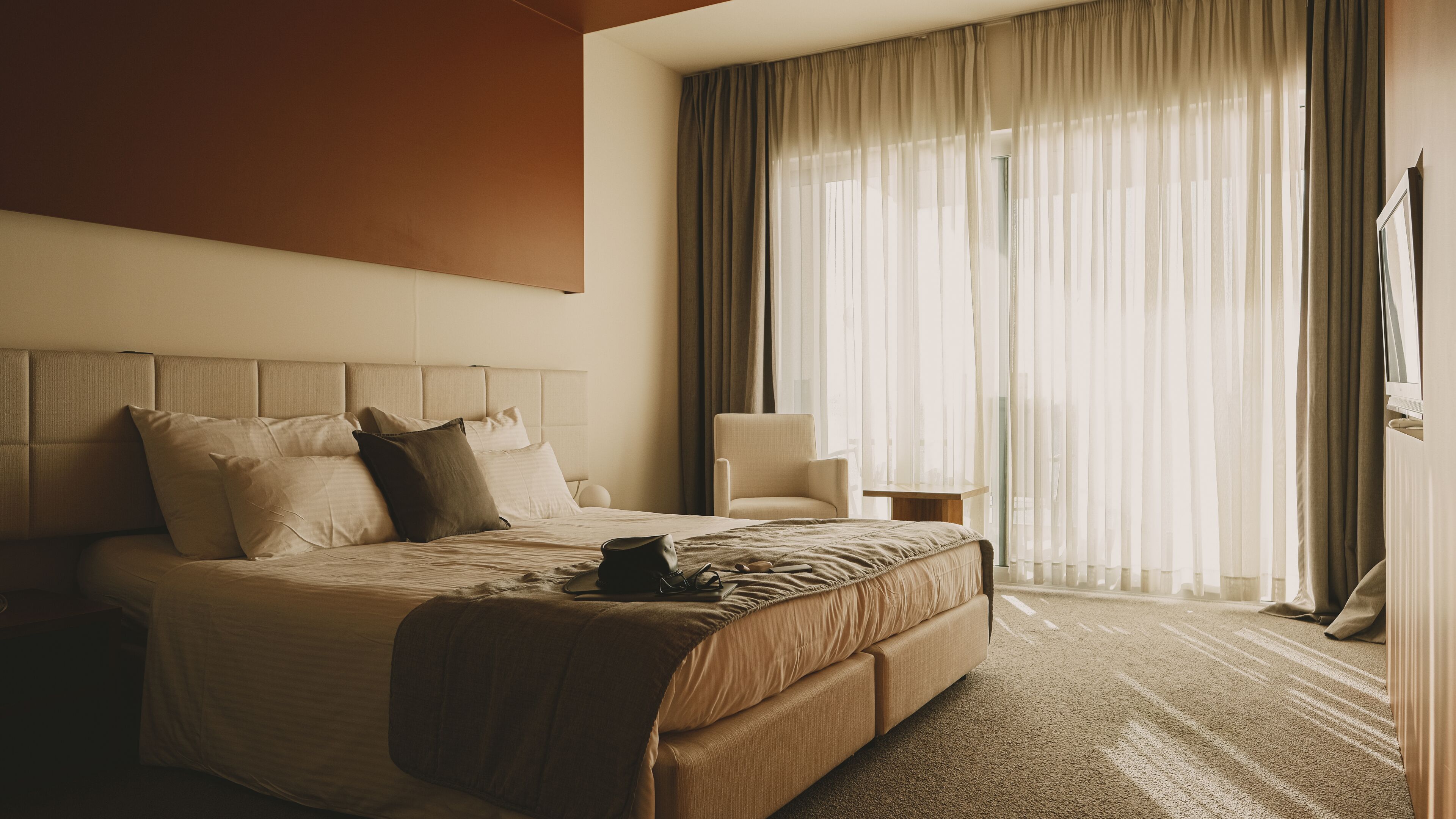 A hotel room with a large bed, a chair, a desk, and a TV.