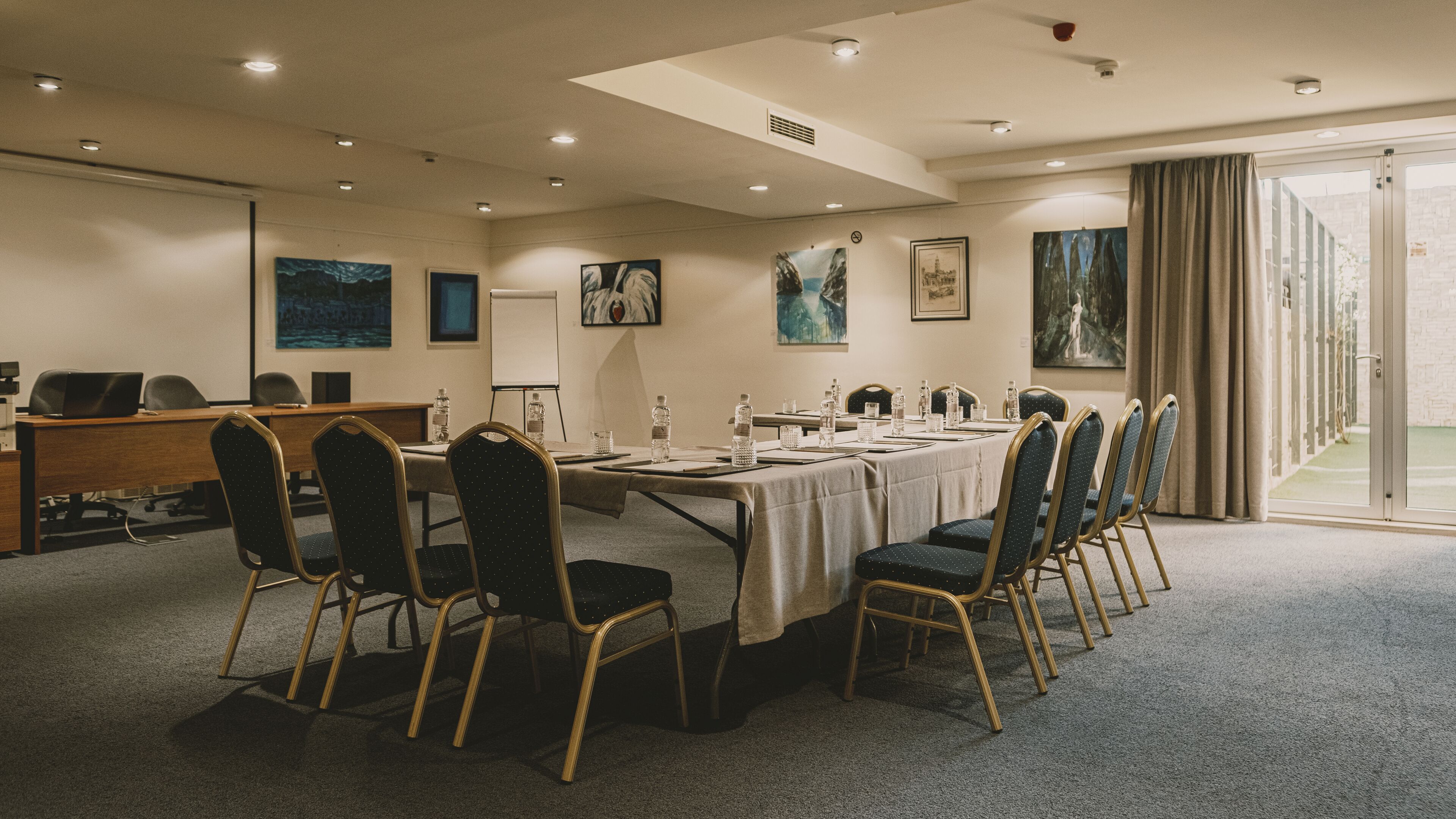 Une salle de conférence avec une longue table, des chaises et des œuvres d’art accrochées aux murs.