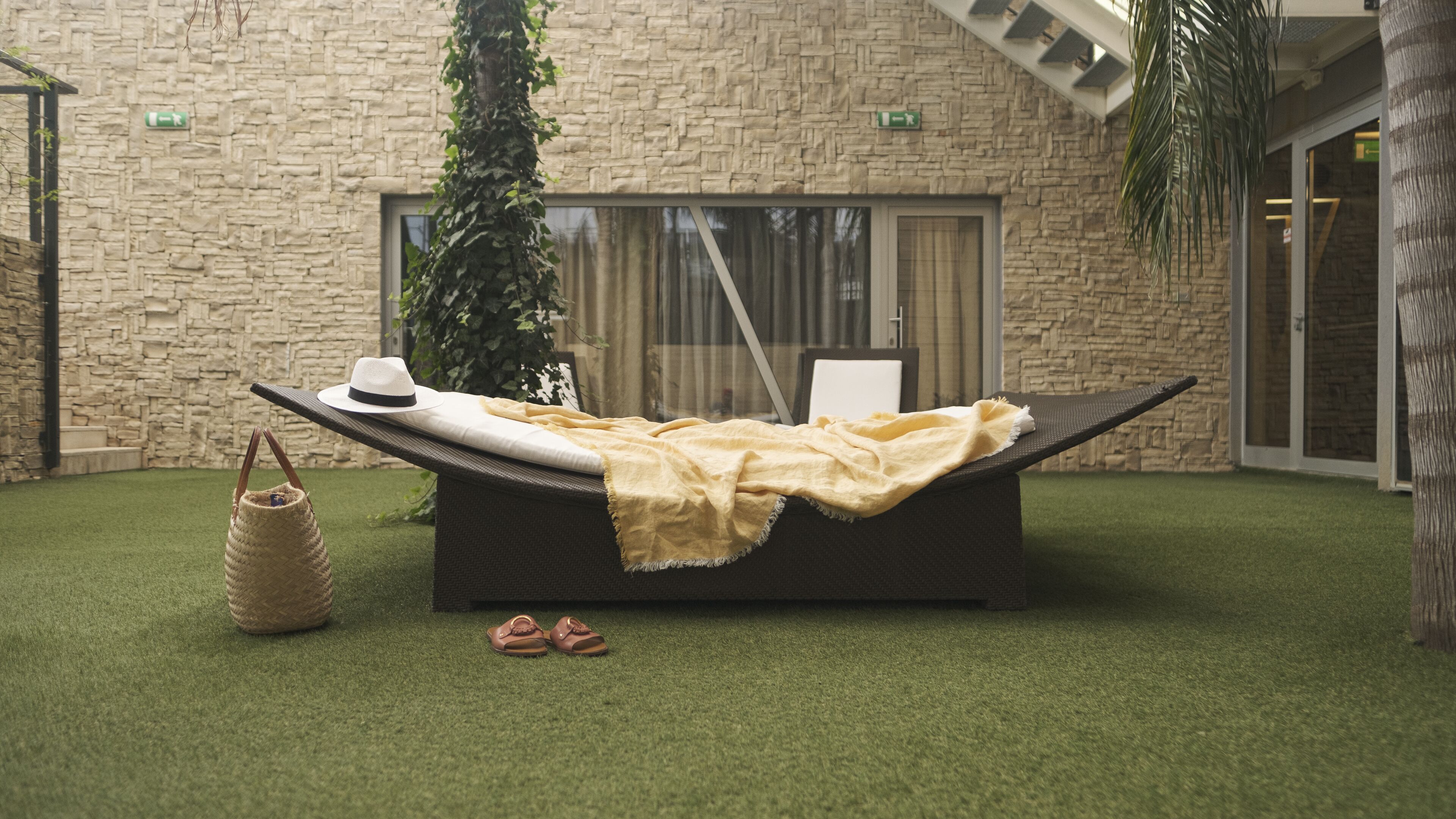 A relaxation area with a lounge chair, a hat, a blanket, and a basket.