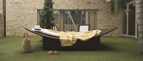 A relaxation area with a lounge chair, a hat, a blanket, and a basket.