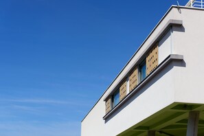 A modern building with a white facade and a window with a unique pattern.