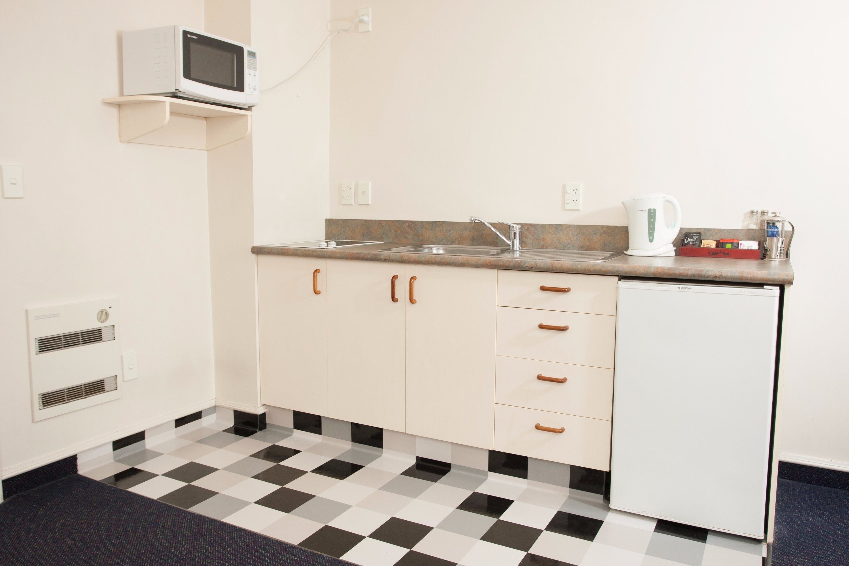 A small kitchenette with a microwave, sink, and refrigerator.