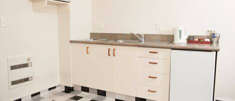 A small kitchenette with a microwave, sink, and refrigerator.