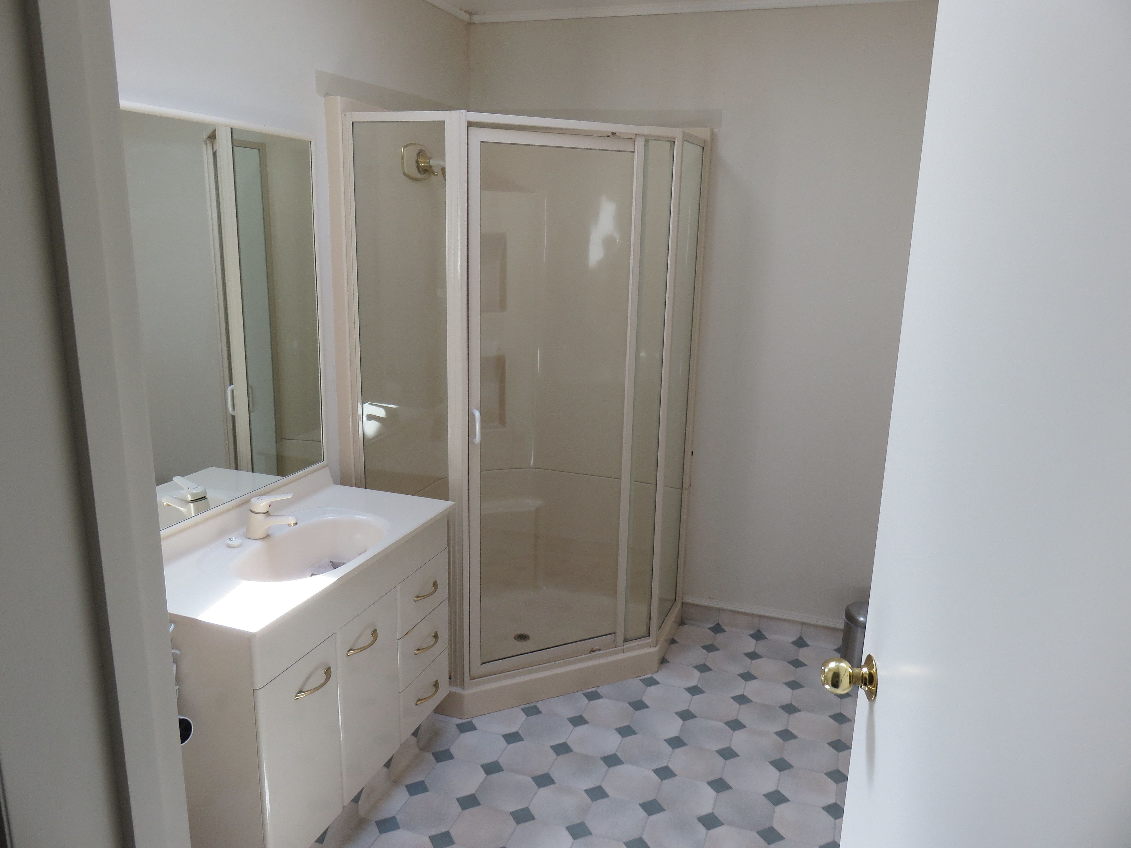 A bathroom with a white sink, mirror, and a glass-enclosed shower.