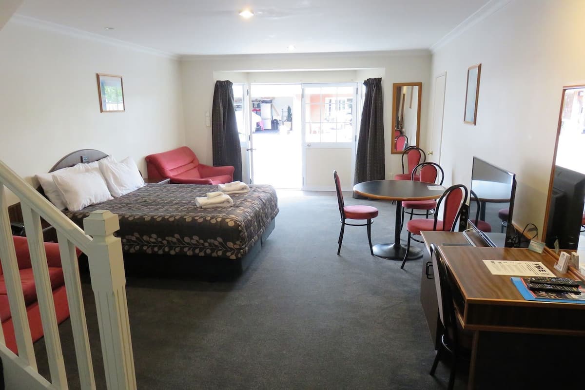 A hotel room with a bed, a desk with a computer, a chair, and a dining table.