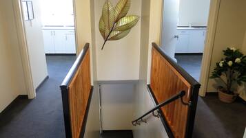 A staircase with wooden handrails and a decorative leaf wall art piece.