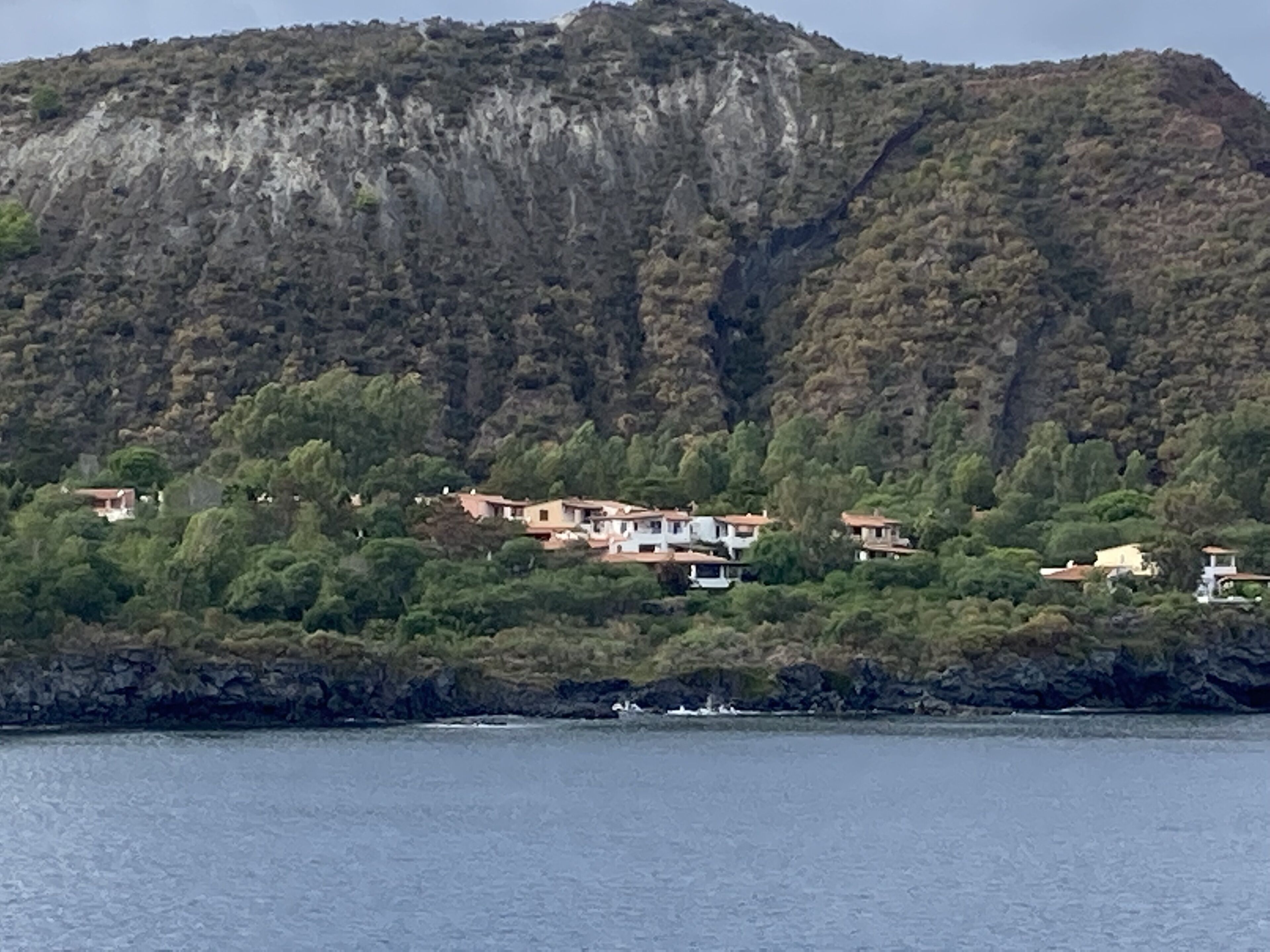 Una propiedad costera con varias construcciones ubicadas entre abundante vegetación en una ladera.