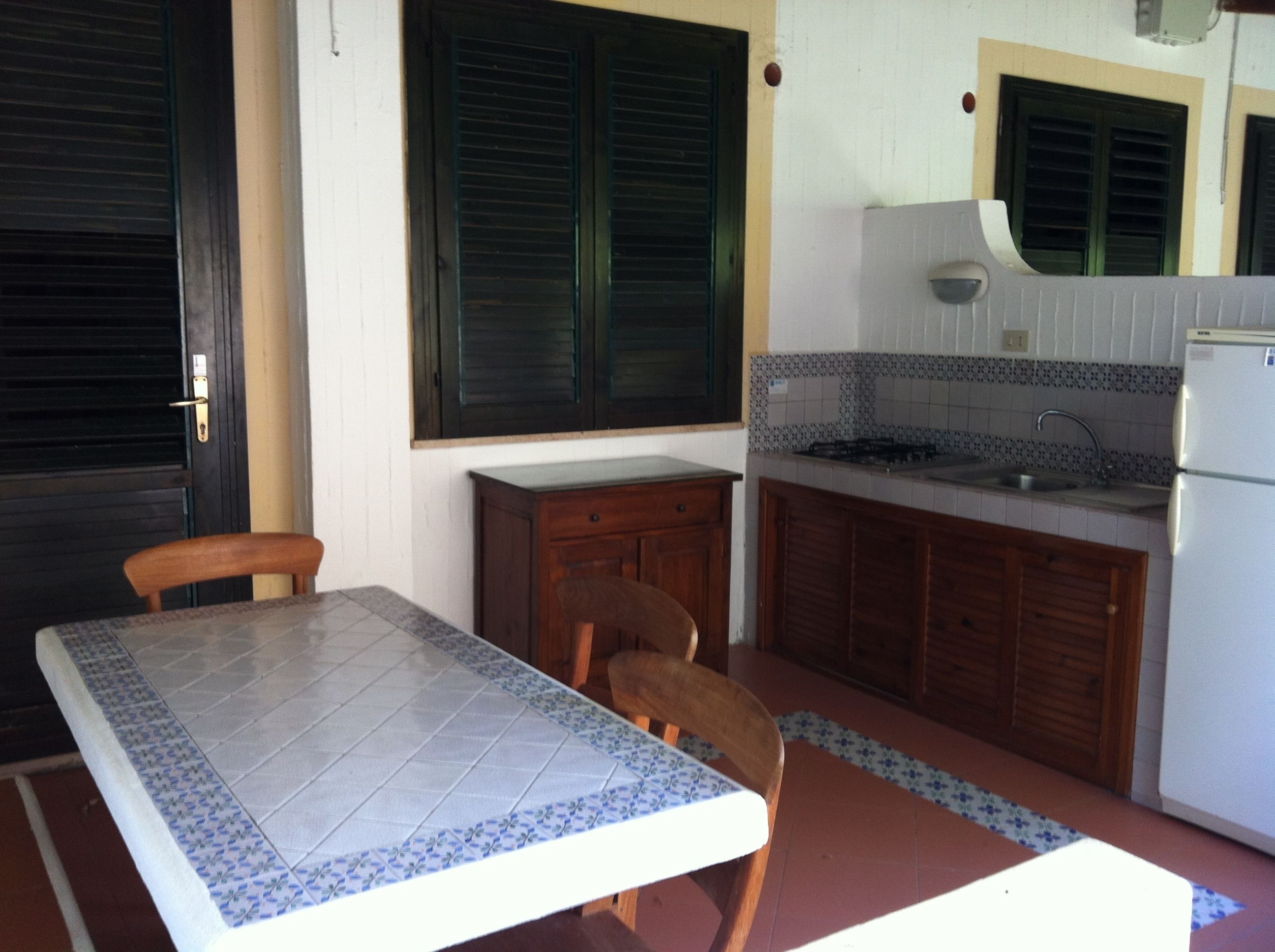 A compact kitchen with a dining table, chairs, a refrigerator, and a sink.