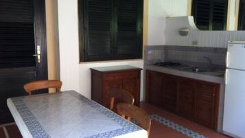 A compact kitchen with a dining table, chairs, a refrigerator, and a sink.