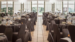 A banquet hall with rows of tables, each set with numbered place settings and floral centerpieces. - Hotel Don Carlos (Huarte)