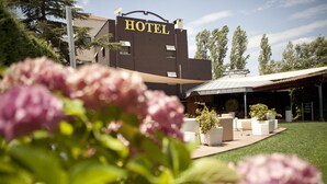 A hotel with a sign, outdoor seating, and a garden. - Hotel Don Carlos (Huarte)