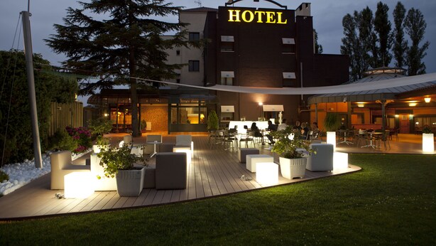 A hotel with outdoor seating, a well-lit entrance, and a large sign. - Hotel Don Carlos (Huarte)