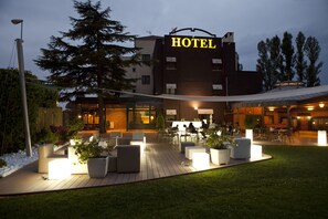 A hotel with outdoor seating, a well-lit entrance, and a large sign. - Hotel Don Carlos (Huarte)