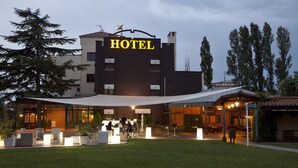 A hotel with a prominent "HOTEL" sign, outdoor seating area, and a covered patio. - Hotel Don Carlos (Huarte)
