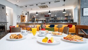 Desayuno con cruasanes, fruta y café en la barra de un hotel.