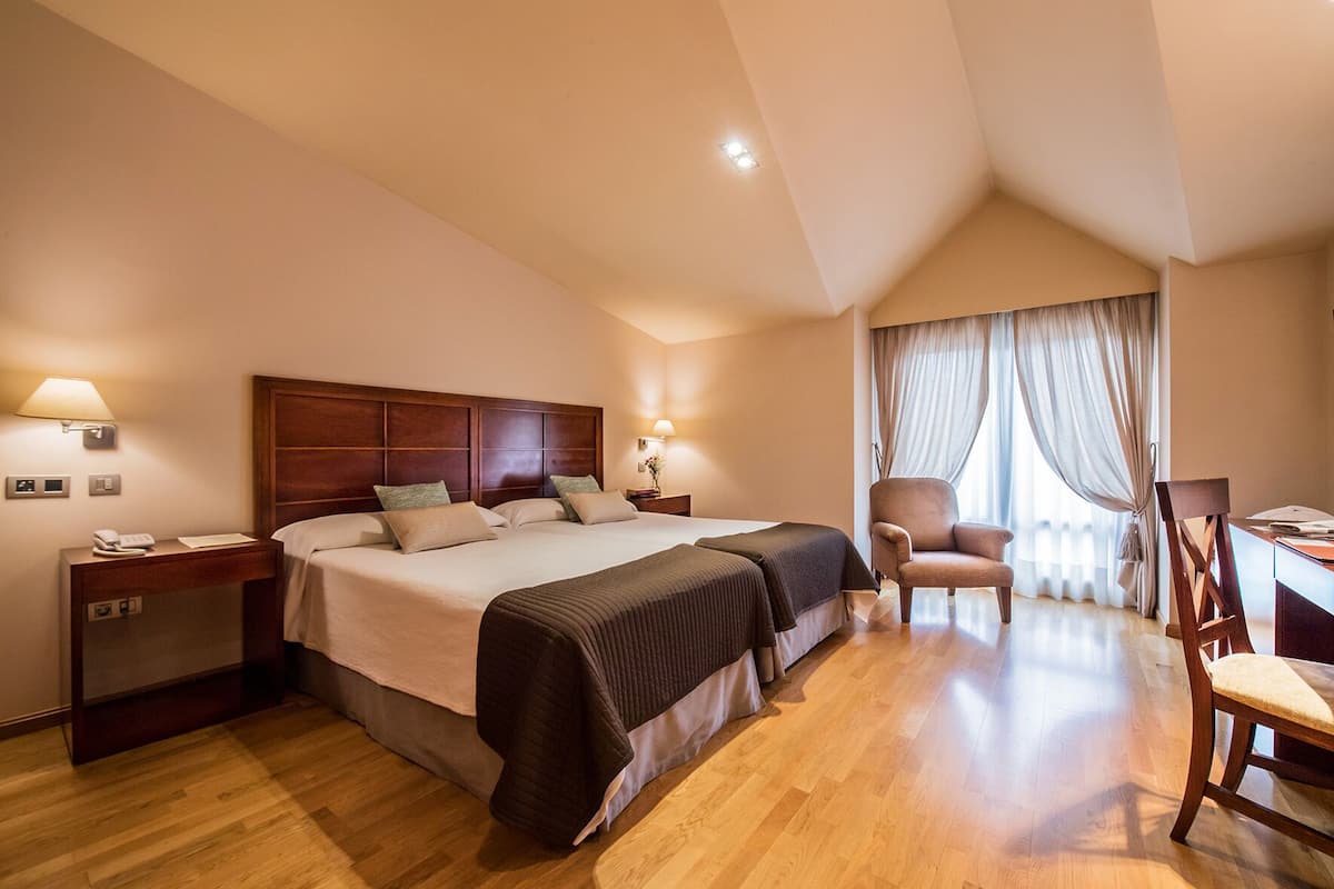 Ein Hotelzimmer mit einem großen Bett, Nachttischen, einem Schreibtisch und einem Sessel.