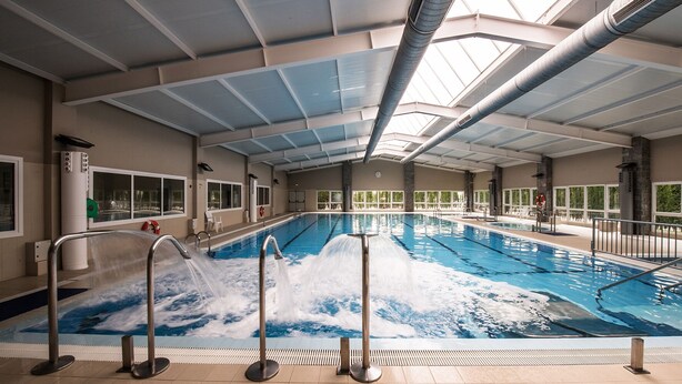 Una piscina interior con agua cristalina, suelo de baldosas y techo con tragaluces.