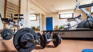 Ein Fitnessraum mit Trainingsgeräten, darunter Kurzhanteln und ein Rudergerät.