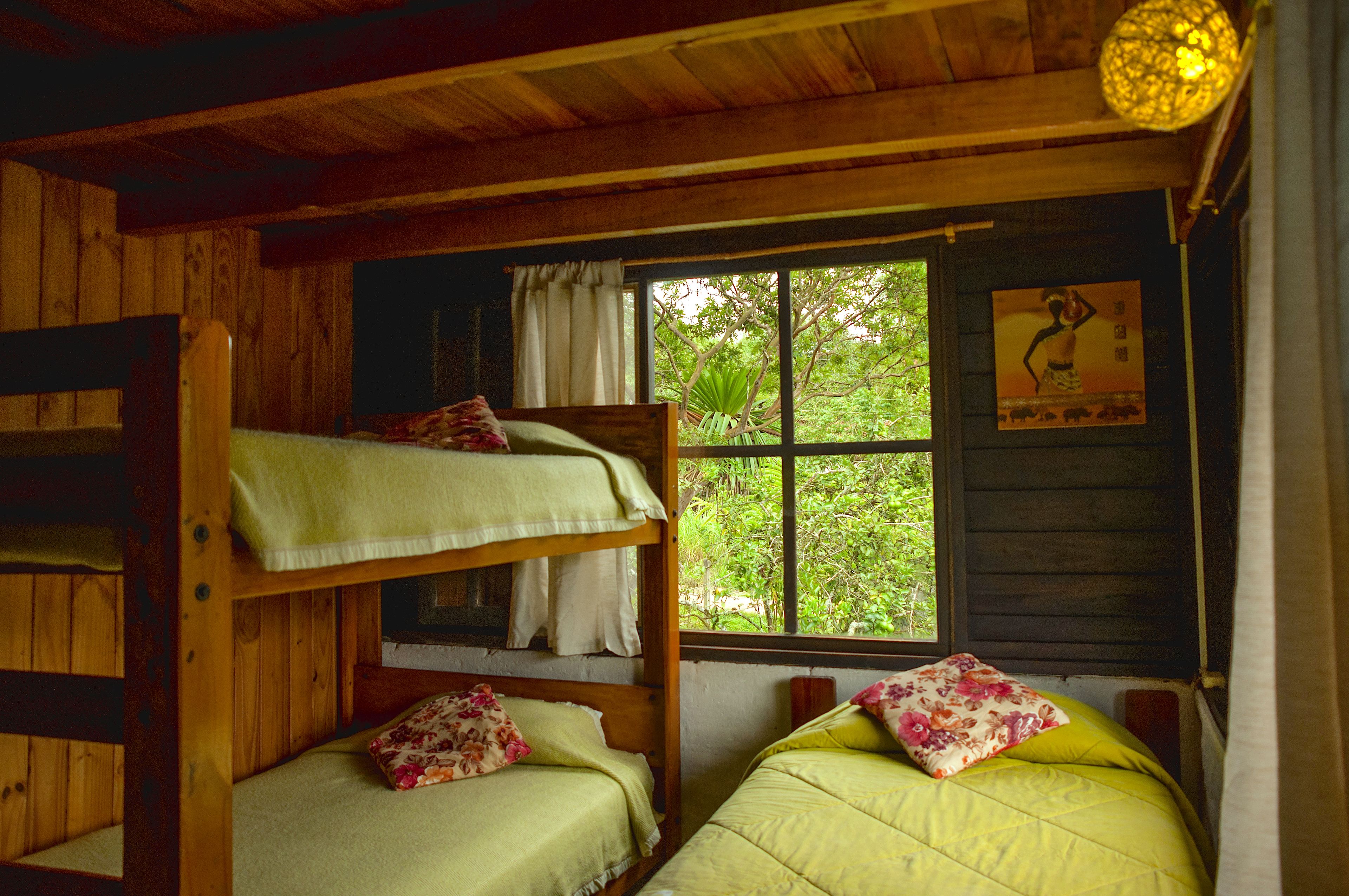 Una habitación de cabaña de madera con literas, una ventana con cortinas y un cartel en la pared.