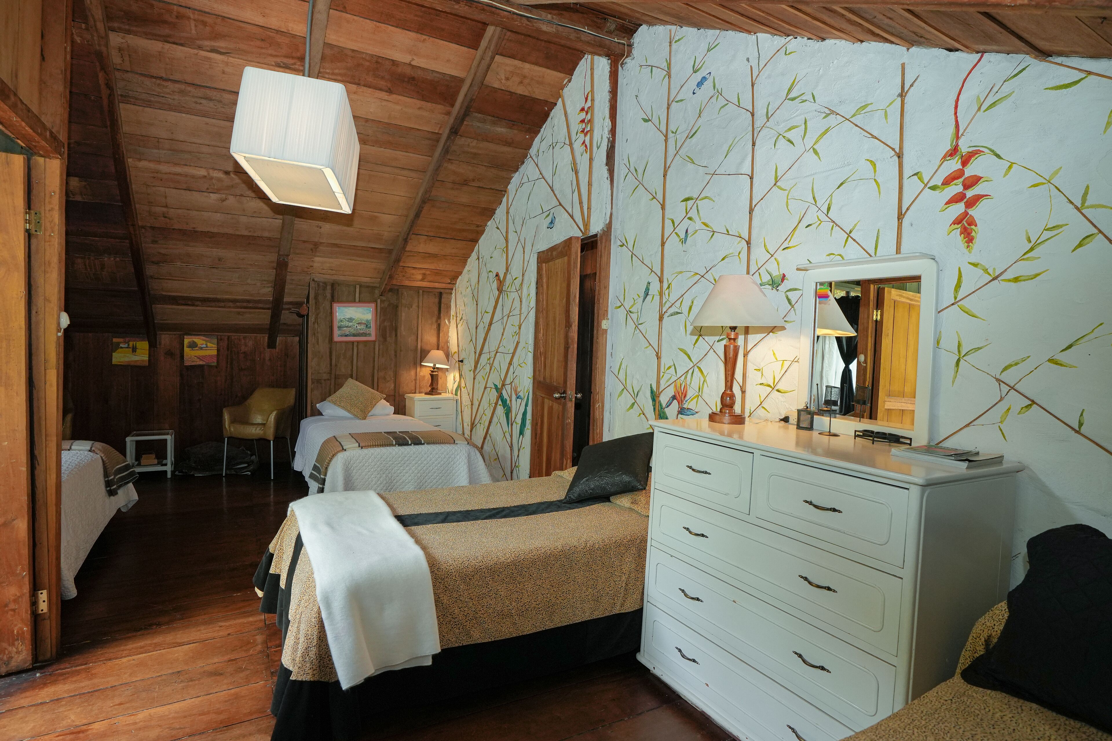 Une pièce confortable avec deux lits, un plafond en bois et une commode avec un miroir.