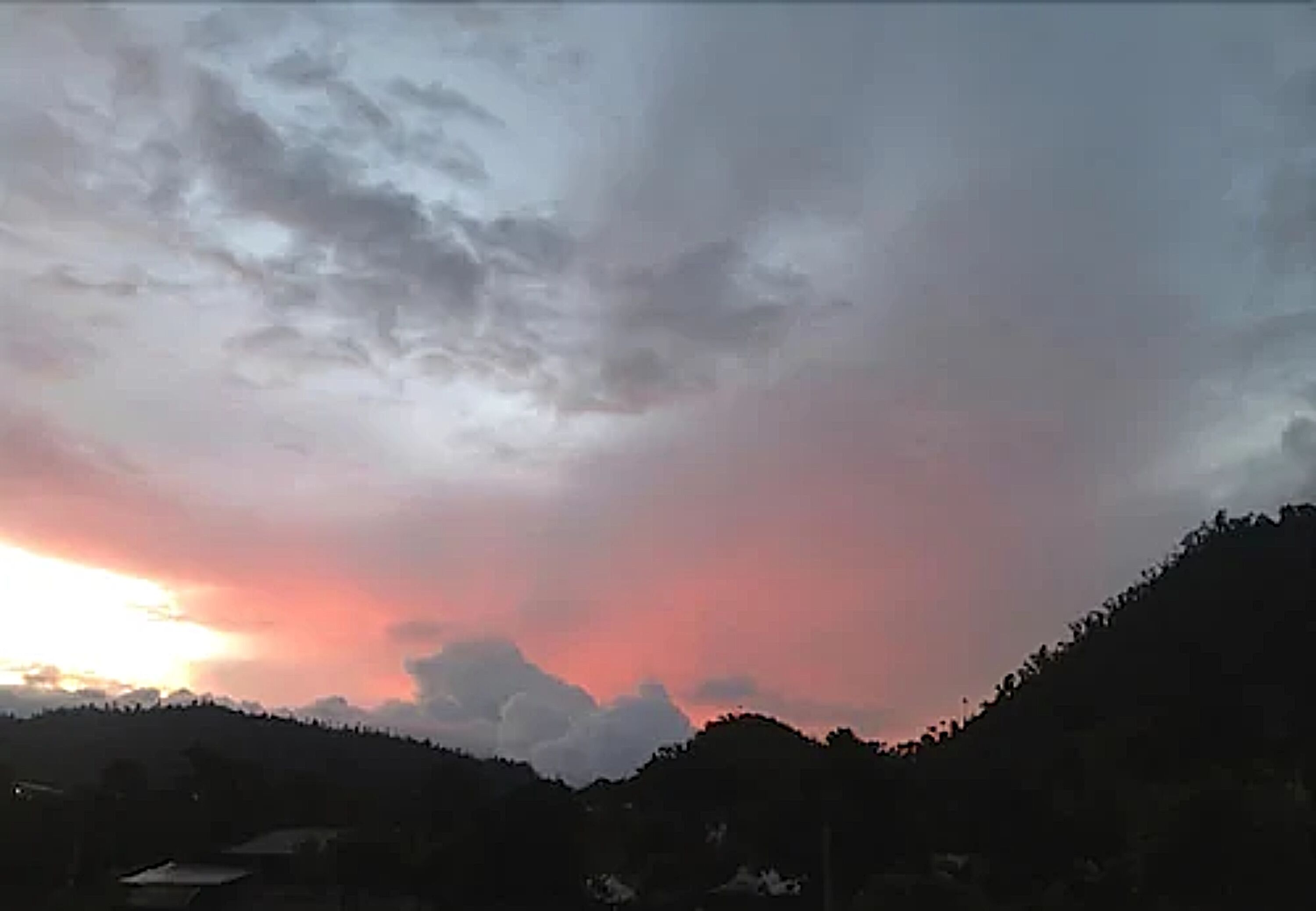 A landscape with a sunset over a hilly area.
