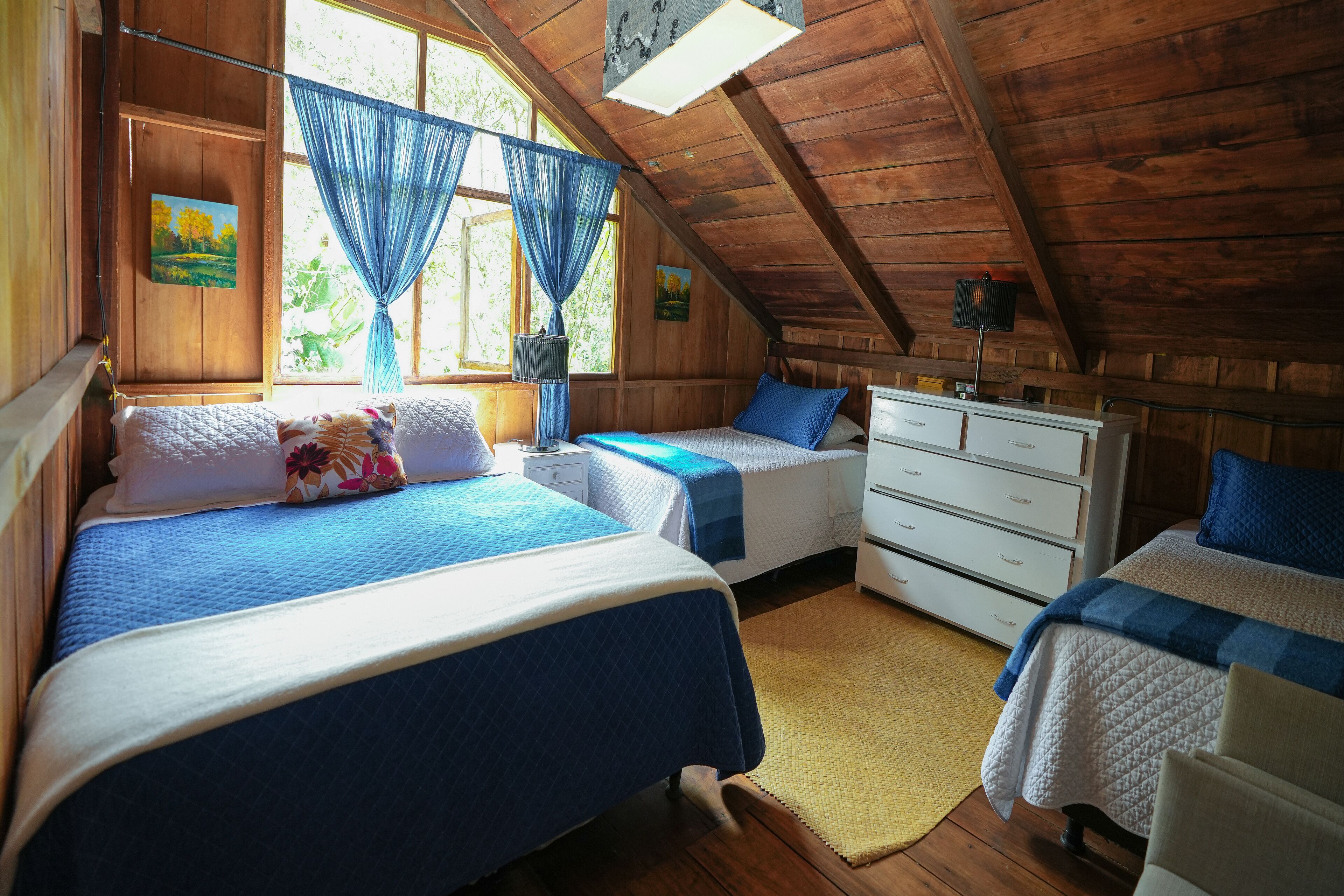 Una habitación con dos camas, paredes de madera y techo inclinado.