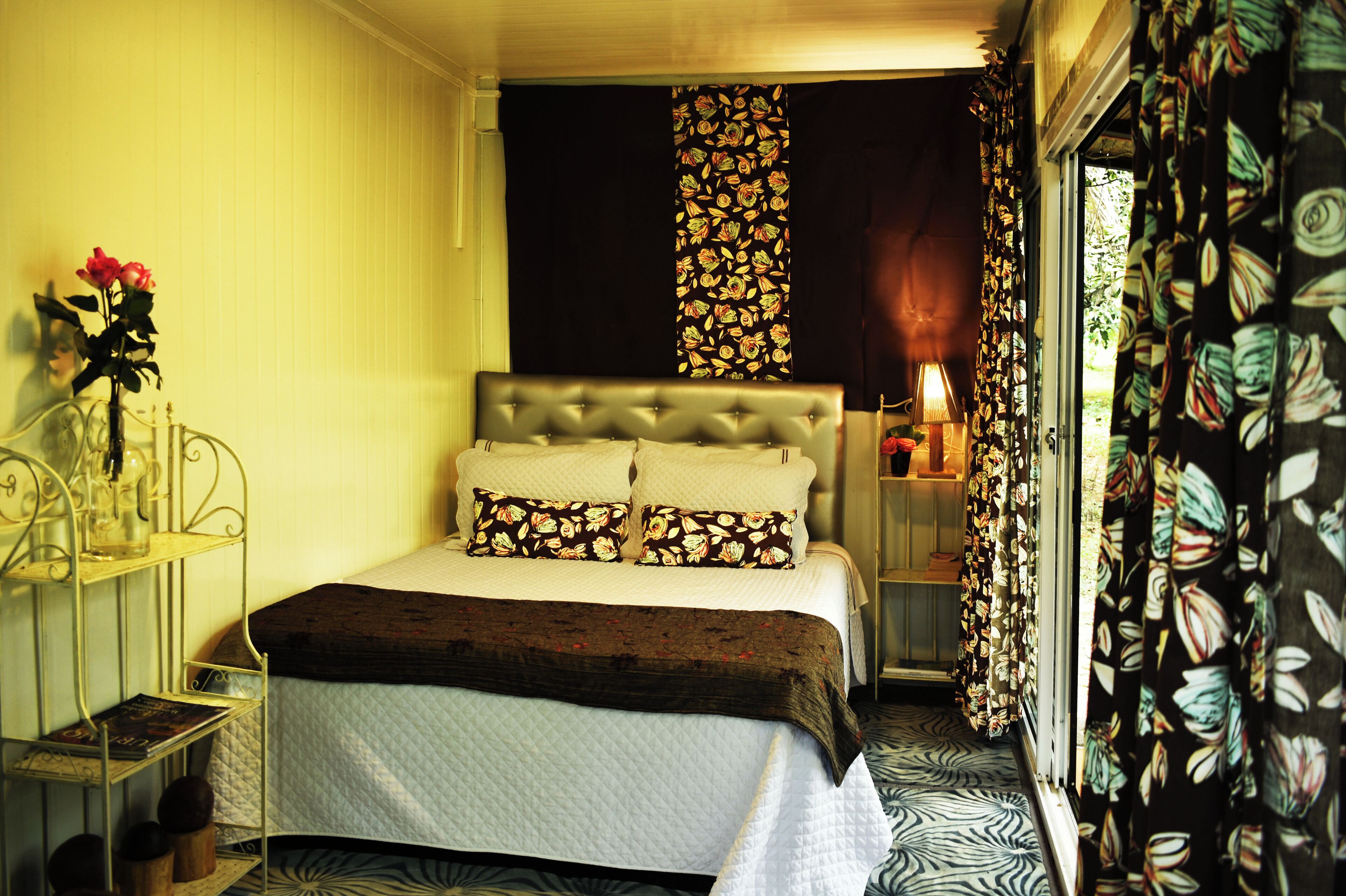 A bedroom with a bed, a bedside table, a lamp, and curtains.