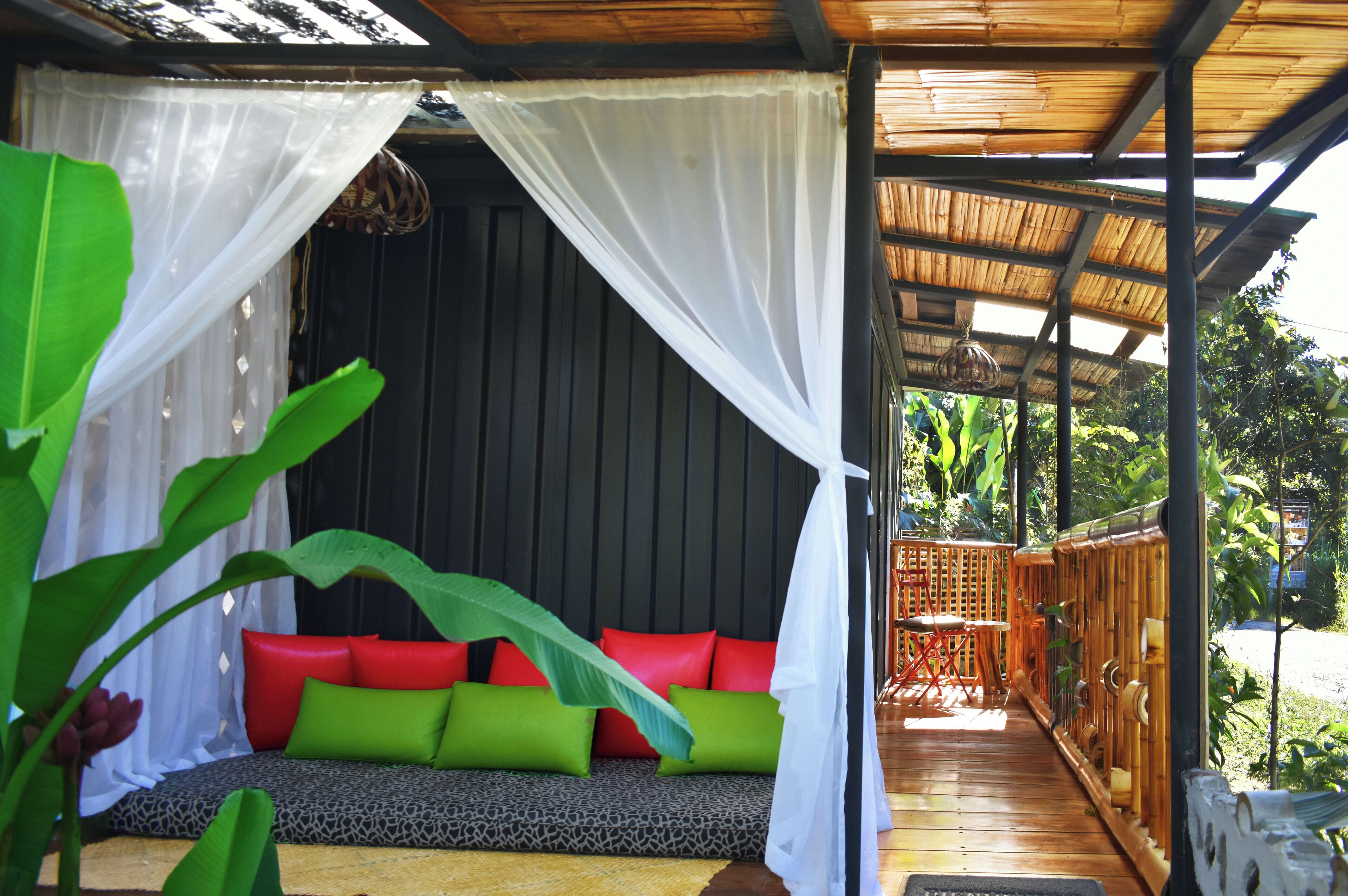 A room with a bed, a bench with cushions, a canopy, and a wooden deck.