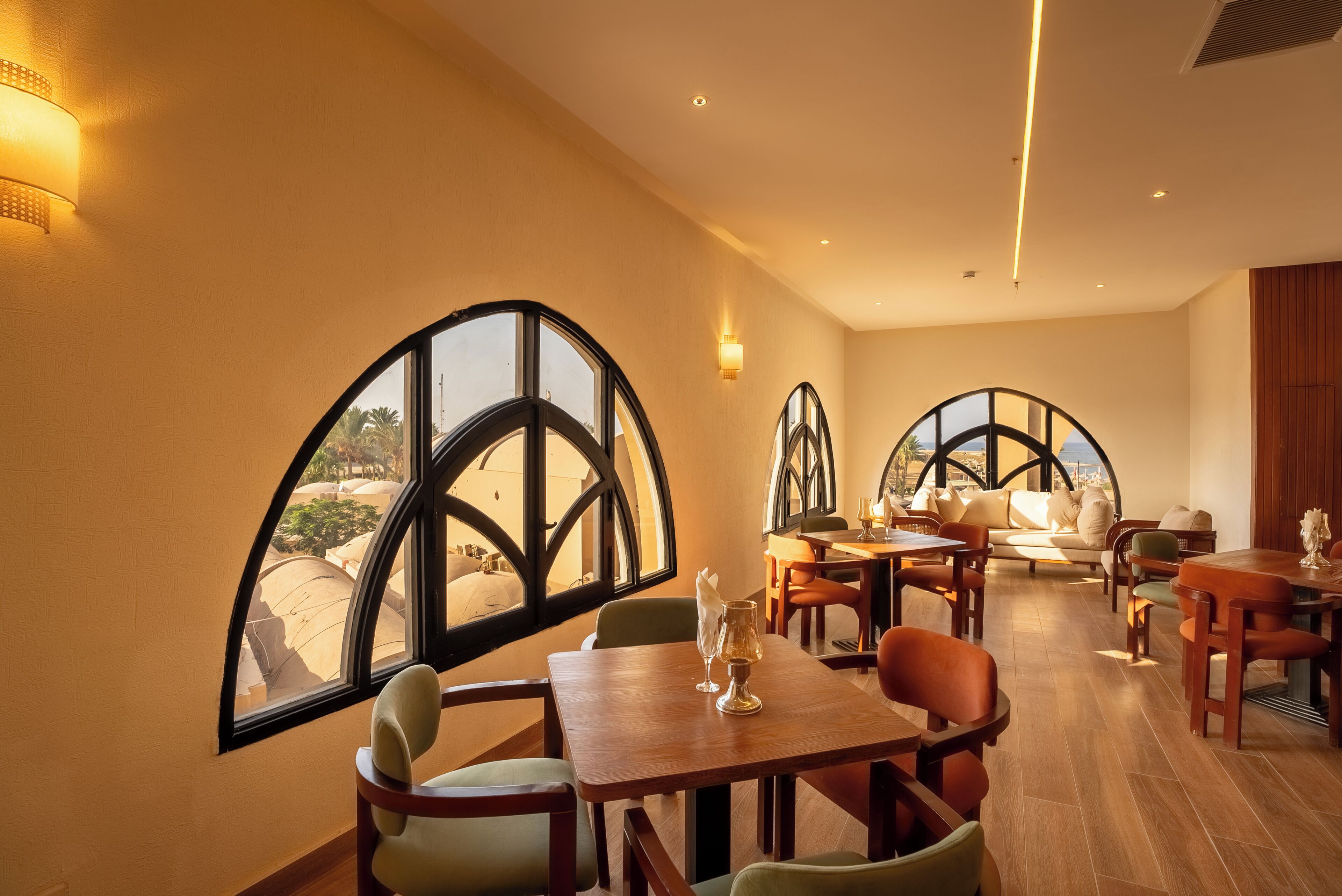 Un comedor con amplios ventanales arqueados, mobiliario de madera y vistas a la ciudad.