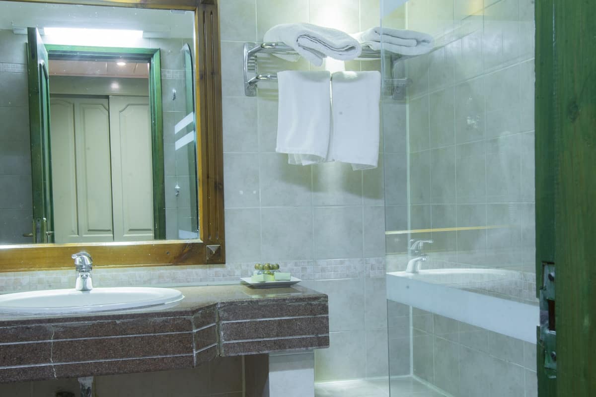 A bathroom with a sink, mirror, and a glass-enclosed shower area.