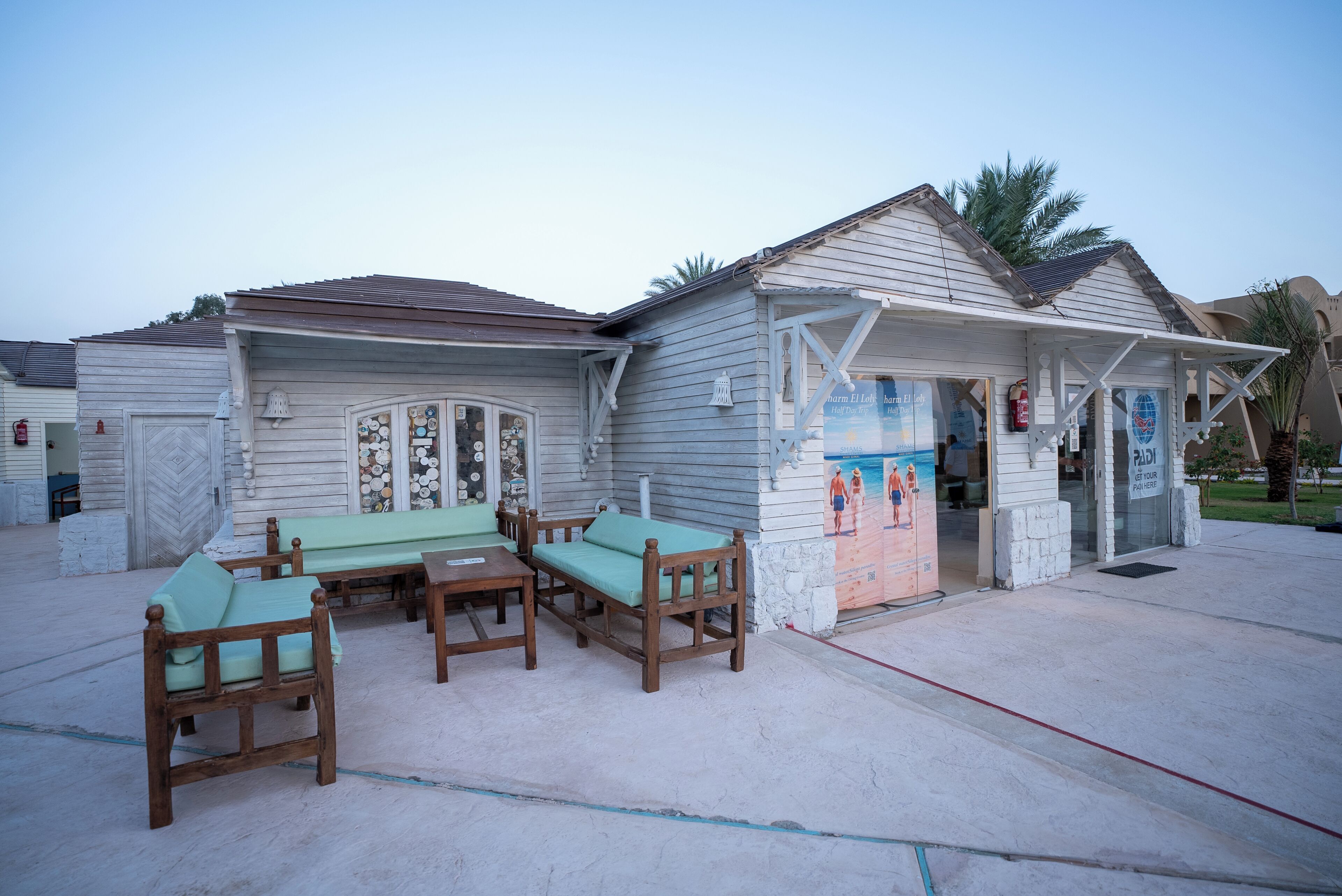 A beachfront building with a covered outdoor seating area and a glass door entrance.