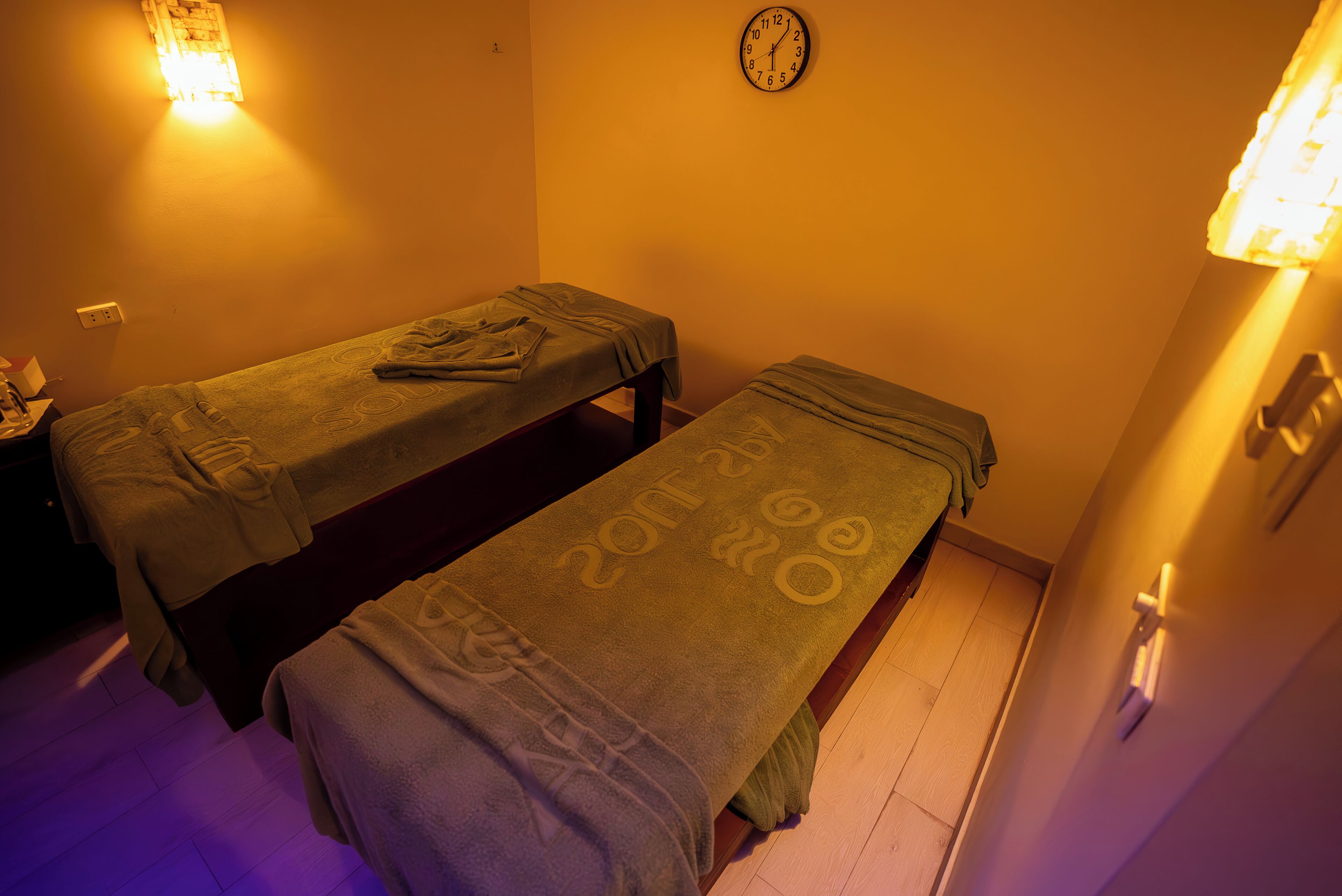 Une pièce équipée de deux tables de massage, d’une horloge murale et d’une prise de courant.