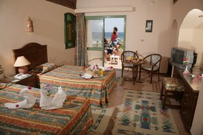 Habitación de hotel con cama, escritorio, silla, televisión y vista al mar.